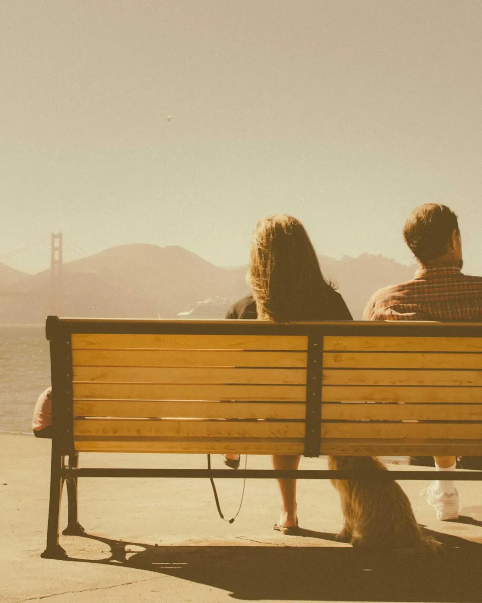 A couple on a bench by the water on the cover of Sam and Alex's wedding film